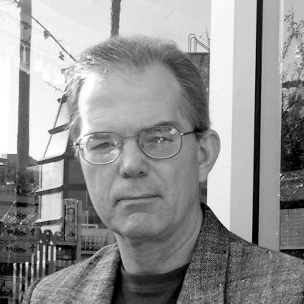 Black and white headshot of a man with glasses