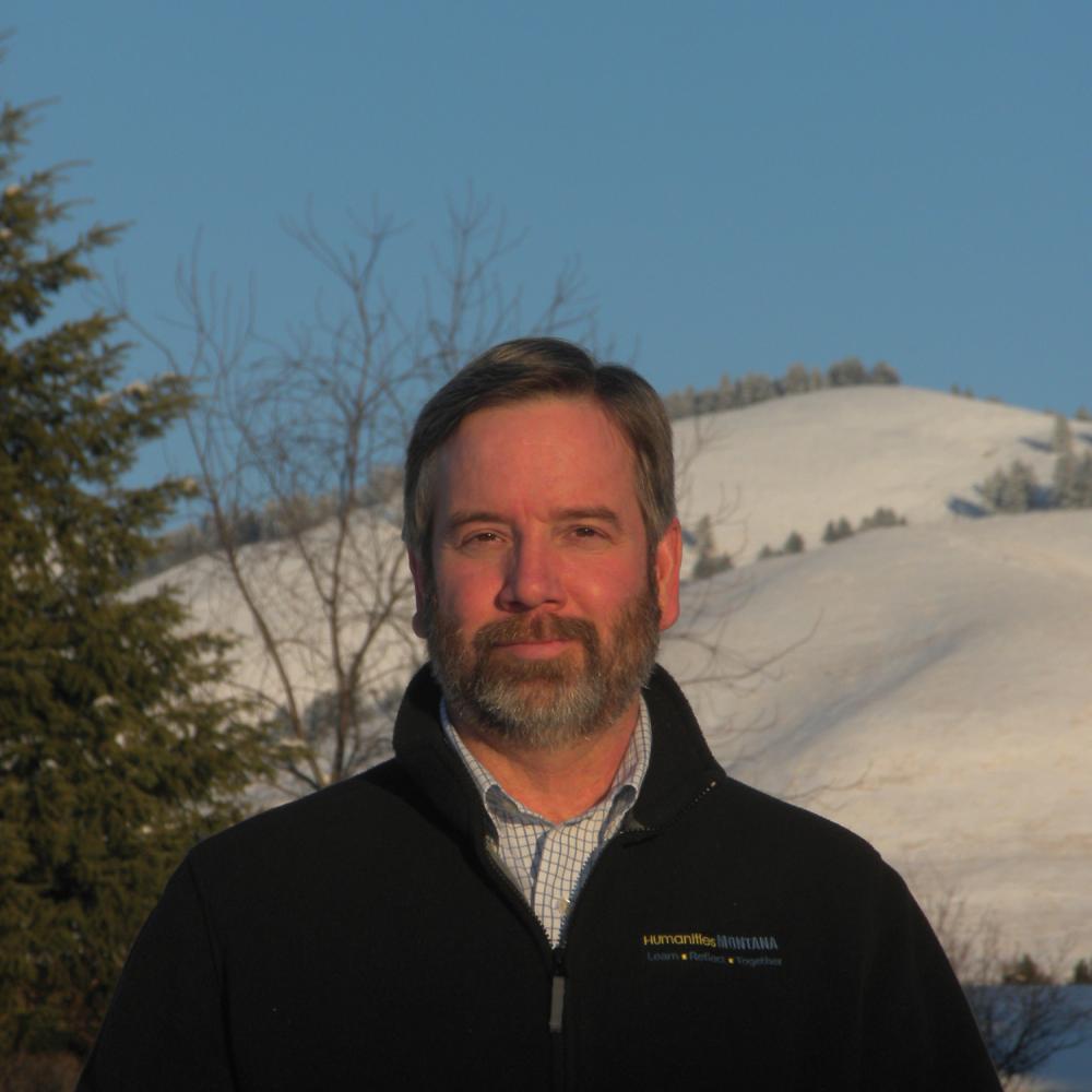 Color photo portait of Ken Egan wearing a black sweater before a snowy background.